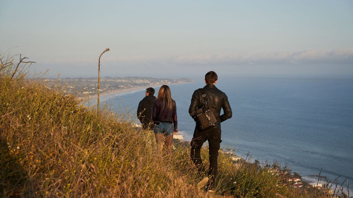 A group of friends walking along a coastal path above the sea